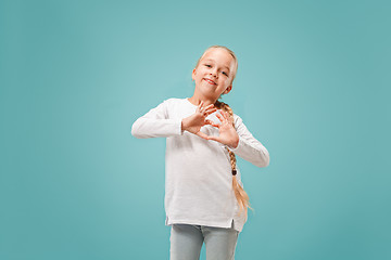 Image showing Beautiful smiling teen girl makes the shape of a heart with her hands on the blue background.