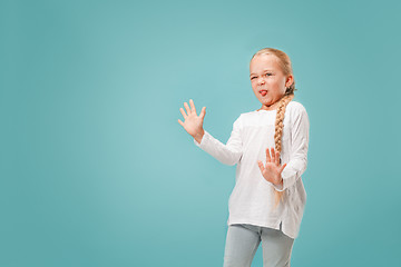 Image showing Doubtful pensive teen girl rejecting something against blue background