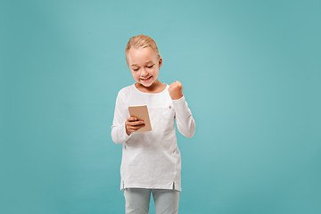 Image showing The happy teen girl standing and smiling against blue background.