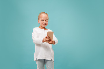 Image showing The happy teen girl standing and smiling against blue background.