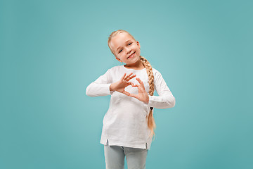 Image showing Beautiful smiling teen girl makes the shape of a heart with her hands on the blue background.