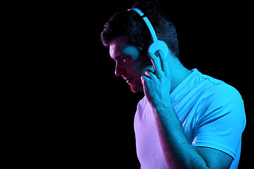 Image showing man in headphones over neon lights of night club