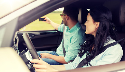 Image showing happy couple in car taking selfie with smartphone