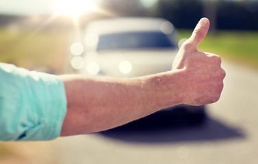 Image showing man hitchhiking and stopping car with thumbs up