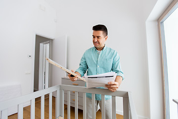 Image showing father with manual assembling baby bed at home