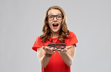 Image showing surprised teenage girl holding pile of glasses