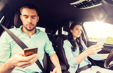 Image showing man and woman with smartphones driving in car