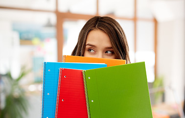 Image showing teenage student girl hiding behind notebooks