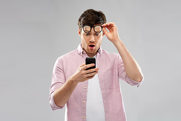 Image showing embarrassed young man looking at smartphone