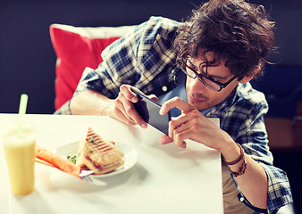 Image showing man with smartphone photographing food at cafe