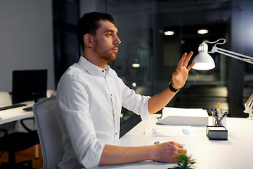 Image showing businessman using gestures at night office