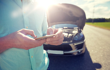 Image showing close up of man with smartphone and broken car