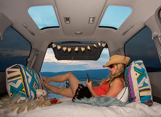 Image showing Woman relaxing in her van using mobile phone