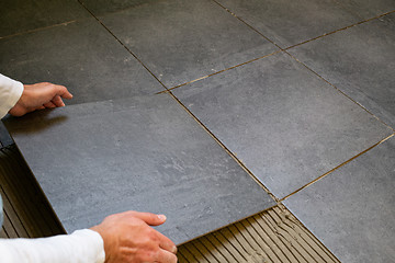 Image showing Tiler installing ceramic tiles on a floor
