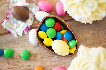 Image showing chocolate egg with candies and cupcakes on table