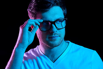 Image showing man in glasses over neon lights in dark room