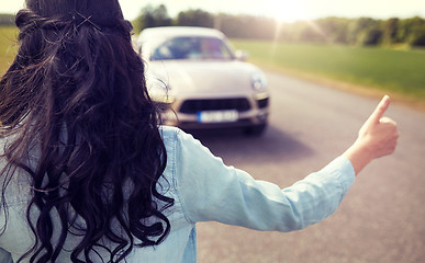 Image showing woman hitchhiking and stopping car with thumbs up