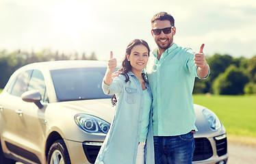 Image showing happy man and woman showing thumbs up at car