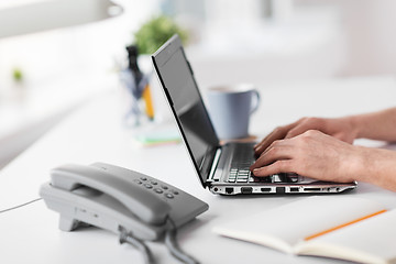 Image showing hands typing on laptop and desk set on table