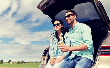 Image showing happy couple with coffee at hatchback car trunk