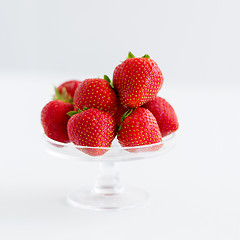 Image showing strawberries on glass stand over white background