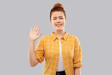 Image showing smiling red haired teenage girl waving hand