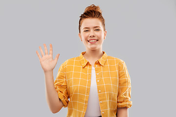 Image showing smiling red haired teenage girl waving hand