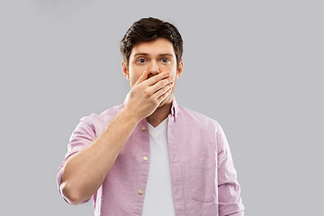Image showing shocked young man covering his mouth by hand