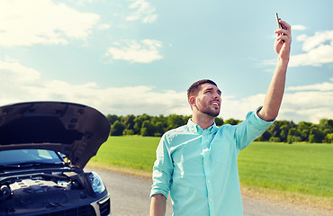 Image showing man with smartphone and broken car at countryside