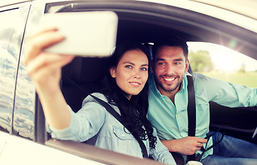 Image showing happy couple in car taking selfie with smartphone