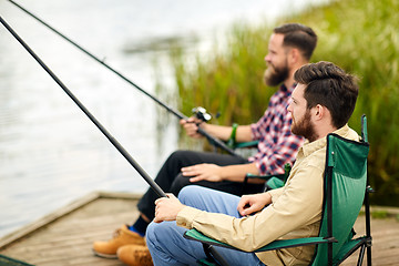 Image showing friends with fishing rods at lake or river