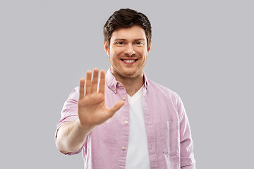 Image showing smiling young man showing his palm