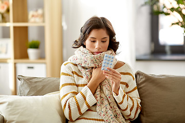 Image showing sick woman in scarf with medicine pills at home