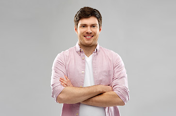 Image showing smiling young man with crossed hands over grey