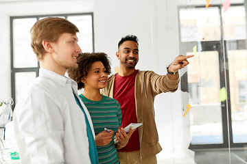 Image showing happy creative team looking at office glass board