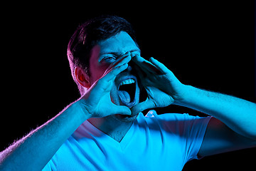 Image showing angry man screaming over neon lights in dark room