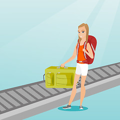 Image showing Woman picking up suitcase from conveyor belt.