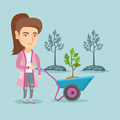 Image showing Caucasian woman pushing wheelbarrow with plant.