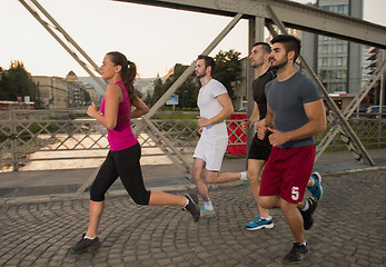 Image showing group of young people jogging across the bridge