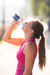 Image showing woman drinking water from a bottle after jogging