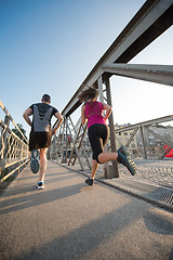 Image showing young couple jogging across the bridge in the city