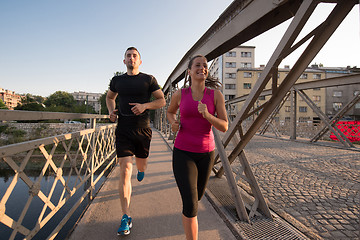 Image showing young couple jogging across the bridge in the city