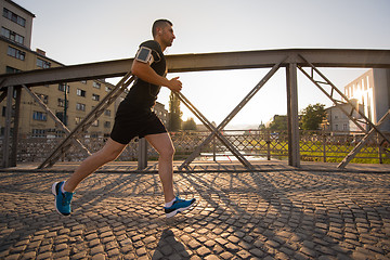 Image showing man jogging across the bridge at sunny morning