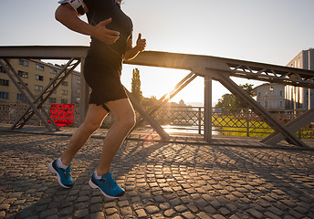 Image showing man jogging across the bridge at sunny morning