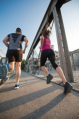 Image showing young couple jogging across the bridge in the city