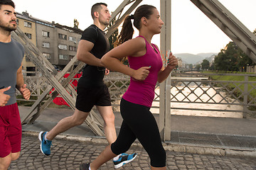 Image showing group of young people jogging across the bridge