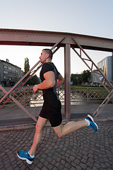 Image showing man jogging across the bridge at sunny morning