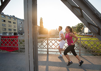 Image showing young couple jogging across the bridge in the city