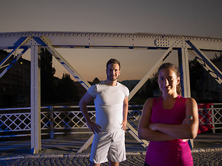 Image showing portrait of couple jogging across the bridge in the city