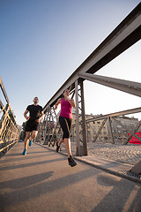 Image showing young couple jogging across the bridge in the city